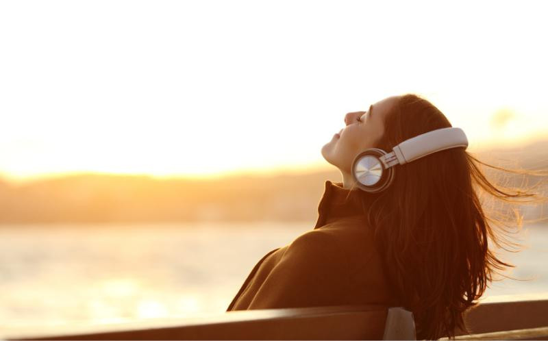 une femme en train d’écouter de la musique face au soleil
