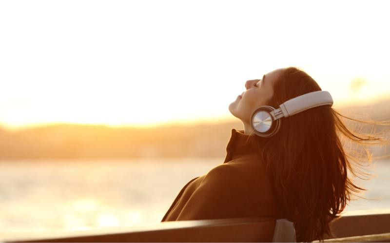 une femme en train d’écouter de la musique face au soleil une femme en train d’écouter de la musique face au soleil
